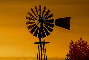 A windmill and top of the latice tower in sunset lighting.