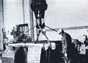 Parsons Turbine. Crane hook in view with cables attached to four points of lower casing. Man standing on right supervising installation.